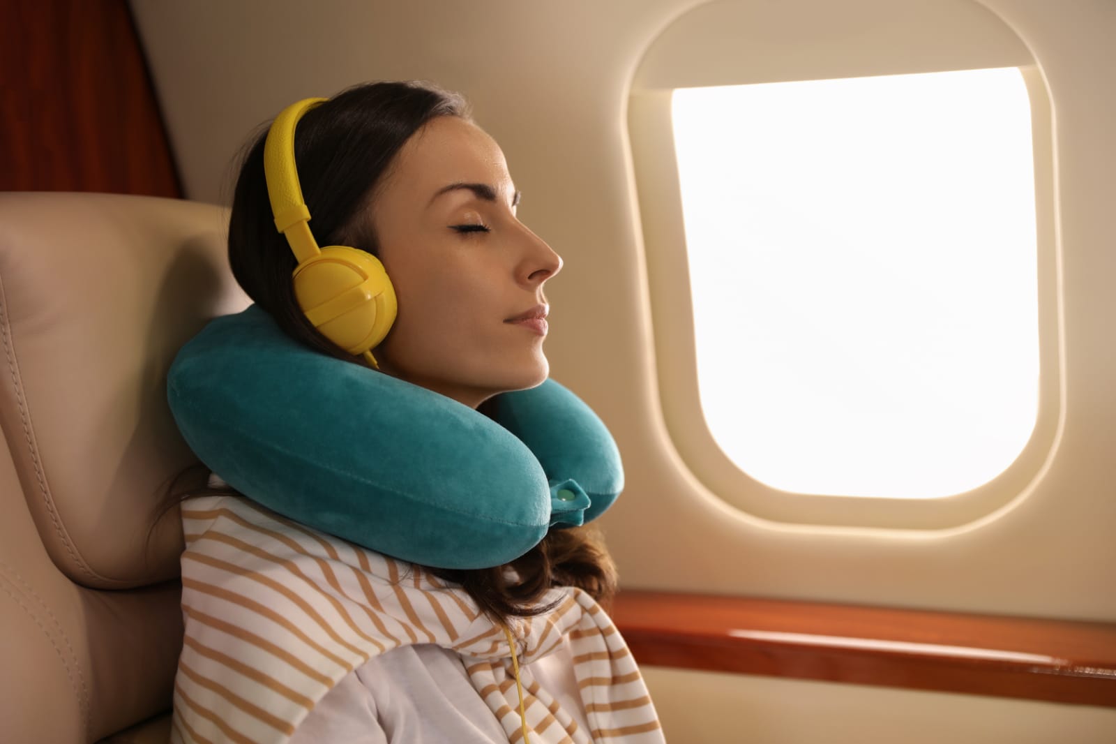 Mulher em avião com travesseiro de viagem